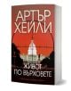 Българско издание на „Живот по върховете“, на чиято корица е изобразена бялата сграда на Капитолия (САЩ) в мерника на червен фон. Заглавието, изписано с удебелени кирилически букви, подсказва, че в историята са вплетени политически интриги.-1-thumb