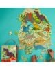 Човек сглобява Пъзел Floss & Rock, Dino - Динозаври, 120 части с цветни динозаври, вулкани и растения на син фон. Кутията с Т-Рекс е поставена до пъзела.-4-thumb