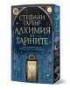 Корицата на "Алхимия на тайните" е с мистични алхимически символи, изящна арка и златист надпис върху тъмносин фон със звезди и луни; част е от съвременна фентъзи поредица.-1-thumb