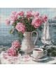 Диамантен гоблен Ideyka - Сутрешни рози: Ваза с розови рози до бяла чаша и чинийка на маса край вода със заден план лодка. По покривката са разпръснати листенца, придаващи ефект на картини с диамантени камъчета.-1-thumb
