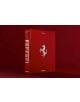 Голяма червена книга с твърди корици, озаглавена Ferrari, със сребърно лого на бял кон и бял текст на гръбчето и корицата, стои изправена на подходящ червен фон - в чест на духа на Ferrari.-2-thumb