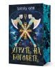 Обложката на "Игрите на боговете - твърда корица" включва богато украсени кръстосани брадви над магически символ със златен текст на кирилица, светещи сини акценти на тъмен фон и намек за Турнир на боговете, воден от Хадес и Зевс.-1-thumb
