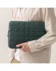 Лице със светлобежова риза държи близо до тялото си Калъф за лаптоп Miquelrius Urban Soft Green 15" / 16". Тъмнозеленият ватиран ръкав е с мрежеста шарка и цип по горния ръб.-5-thumb