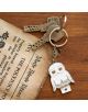 Комплект ключове на ключодържател с Grupo Erik Harry Potter - Hedwig ключодържател, оформен като бухал със златни акценти и червена звезда, почива върху дърво в близост до състарена хартия за отвара от полижуи - идеален за феновете на Хари Потър.-3-thumb