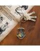 Ключовете са закачени на Ключодържател Grupo Erik Harry Potter - Hogwarts с цветна емблема Хогуортс, поставен върху дървена повърхност до илюстрирани страници от магическа книга.-4-thumb