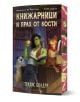 Корица на книгата за Книжарници и прах от кости - с порезка: Жена със зелена кожа и ябълка чете на бюро, а към нея се присъединяват куче и плъх с шалвари. Българското заглавие се появява над рафтове с книги на заден план.-1-thumb