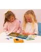 Две млади момичета се усмихват, докато играят с Комплект магнитни игри Floss & Rock Fun - Dino, увлекателен избор за игри за пътуване на деца, включващ магнитни карти, дъска с мрежа и фигури за игра. Те се наслаждават на забавното занимание заедно.-4-thumb