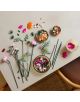 На масата е изложен „LEGO Botanicals: Красив букет с розови цветя“, състоящ се от цветни цветя, зелени стъбла и купички с сглобени и несглобени части от строителния комплект за възрастни.-4-thumb