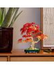 Малък слънчев букет от серията „LEGO Botanicals“ стои върху дървена повърхност до саксийно растение и зелен химикал, на фона на текстурирана стена с декоративни картини.-6-thumb