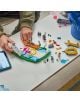 Някой сглобява комплекта „LEGO Editions Лионел Меси“ върху бяла маса, по която са разпръснати LEGO парченца, има телефон, а в десния край се вижда син предмет.-6-thumb