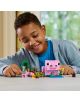 Едно момченце се усмихва, докато си играе с цветни LEGO кубчета, сред които е и комплектът „Къщата на прасенцето“ от серията LEGO Minecraft, в който на бяла маса в стаята са разположени голямо розово прасенце, малки животни и миниатюрни растения.-9-thumb