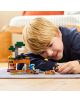 Малко момче с руса коса се усмихва, докато си играе на пода с комплекта „LEGO Minecraft: Минна експедиция с броненосец“, който включва малки фигурки и блок TNT, в уютна стая, на фона на която се вижда легло.-8-thumb