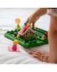 Детска ръка протяга ръка, за да постави парче на Логическа игра Smart Games: Хензел и Гретел, с къщичка за играчки, парчета с форма на бонбони и миниатюрна фигурка, подредени върху бяла покривка.-3-thumb