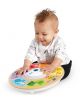 Усмихнато бебе седи на пода и си играе с Музикална играчка Hape Baby Einstein, сензорна - цветна, кръгла играчка с илюстрации на животни и бутони. Бебето е облечено в бяла риза с черни дунапрени и черни панталони.-4-thumb