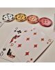 Две карти за игра и четири чипа за покер със звездна шарка лежат върху бяла повърхност, напомняща мотиви от Dragon Ball - идеални за рунд Texas Hold'em или за съвместното забавление на "Настолна игра: Бандата.-4-thumb