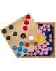 Настолна игра Pig Hole включва дървена дъска за игра, цветни топчета, бяло колче, зарче и множество малки розови фигурки на прасета в кутия, частично покрита от наклонената дъска.-5-thumb