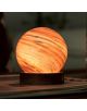 Настолна лампа Gingko AstraGlass Light Mini Polar Cloud има декоративна ръчно издухано стъкло във вихрови оранжеви и кафяви шарки върху тъмна дървена основа, която свети топло като миниатюрна планета, когато е поставена на закрито.-6-thumb