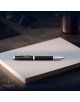 Вдъхновената от авиацията писалка Parker IM Legacy Of Flight лежи върху затворен тефтер до слънчеви очила, чаша и таблет. Логото на Parker и надписът "EST. 1888" се виждат в долния ляв ъгъл.-3-thumb