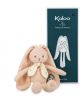 The плюшена играчка Kaloo - зайче, оранжев, 25 см с дълги уши и шарен шал стои пред тъмносиня кутия Kaloo с бяла илюстрация на зайче и логото - идеалната бебешка играчка.-3-thumb