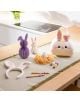 На масата има великденска украса: сгъваеми хартиени зайчета Legami - Hoppy Easter, бяла кошница със зайче, лента за глава със заешки уши, материали за рисуване, цветни моливи и боядисано яйце върху бежова подложка - идеално за великденски забавления!.-9-thumb