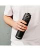 Човек в бяла тениска държи стоманена бутилка Kambukka Elton Insulated Nightfall, 0.600 лв, със Snapclean система и видимо близо до основата. Фонът е изчистен и неутрален.-6-thumb