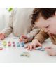 Две деца рисуват малки дървени фигури на бяла маса с пастелни бои - перфектно забавление с Творчески комплект Totum Stitch - Направи и оцвети гипсови фигури.-3-thumb