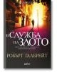 Корицата на книгата "Корморан Страйк, книга 3: В служба на злото" показва детектив, който върви по сенчеста улица, осветена от светещи улични лампи, а българското заглавие и името на автора са подчертани в оранжеви и жълти тонове.-2-thumb
