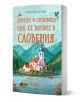 Книгата "Замъци и сливовица - как се влюбих в Словения" представя илюстрирана църква до езеро, заобиколена от планини, лодки и дървета на фона на красива Словения.-1-thumb