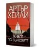 Българско издание на „Живот по върховете“, на чиято корица е изобразена бялата сграда на Капитолия (САЩ) в мерника на червен фон. Заглавието, изписано с удебелени кирилически букви, подсказва, че в историята са вплетени политически интриги.-1-thumb
