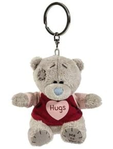 Ключодържател To You - Hugs е плюшен ключодържател Tatty Teddy със сива козина, син нос и червена риза с розово сърце и надпис "Hugs". То е с прошити детайли и надпис "Me to You" (Аз за теб) на лявото му краче - очарователен подарък.