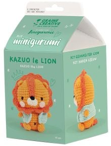 Зелена кутия от Graine Creative с комплект за плетене на една кука за изработване на малко лъвче на име Казуо. Кутията изобразява очарователно оранжево и жълто лъвче в анимационен стил. Текстът е на няколко езика, включително "Комплект за плетене Амигурум