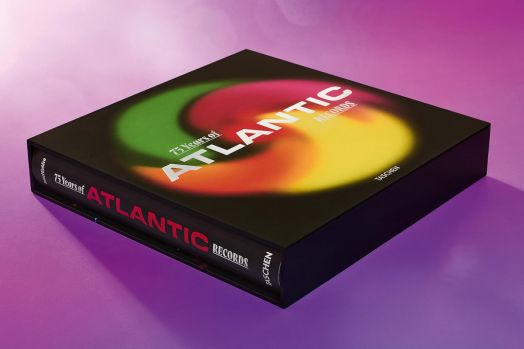 Книгата "75 години Atlantic Records" има цветна вихрова корица и е изложена върху розова повърхност. Изданието на Taschen изследва фотографската история на лейбъла и наследството на соул музиката.-5