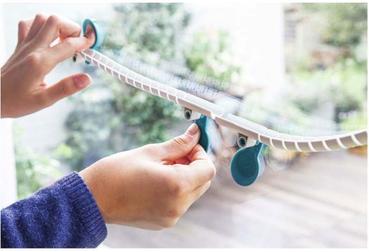 Някой прикрепя Детска игра Kosmos - Gecko Run Big Box пластмасова пътека със сини вендузи към прозореца, вероятно за каца за котки или хамак. През стъклото се виждат зеленина и външни пейзажи.-5