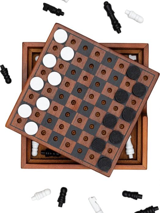 Комплектът Iron & Glory - Шах и Дама включва дървено табло с черни и бели пулове, подредени върху кутия; някои фигури са наоколо, други са вътре в отворената кутия под наклоненото табло.-3