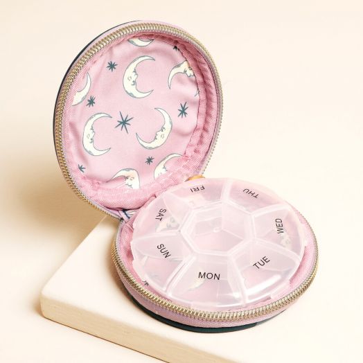 Отвореният Калъф за хапчета DesignWorks Ink - Teal Moon показва розовата си облицовка с луни и звезди, като държи кръгъл седмичен органайзер за хапчета, обозначен с дните от седмицата.-5