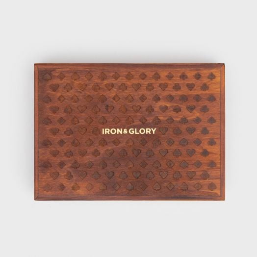 Правоъгълна дървена кутия с гравирани спатия и купа върху капака и златен надпис IRON & GLORY. Карти за игра Iron & Glory Big Deal - идеални като луксозен подарък или комплект за игри. Фонът е бял.-2