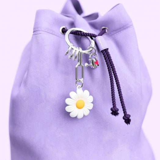 Раница с шнур в лавандулов цвят и лилава корда има Ключодържател Metalmorphose - Daisy, украсен с бяла маргаритка и метални акценти, прикрепен към чантата. Фонът е в съответстващ лавандулов нюанс.-4