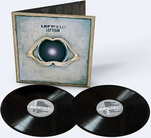 Две черни винилови плочи с надпис "Leftfield - Leftism (2 VINYL)" лежат пред емблематичната електронна музикална албумна обложка, на която е изобразен говорител с челюстна кост в синьо-сиво. В горната част са отпечатани заглавието 2023 преиздание и изпълн