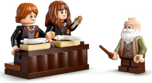 Две минифигурки на ученици от серията „LEGO Harry Potter“ стоят зад чиновете с магически пръчки, водени от възрастен магьосник в класната стая от комплекта „LEGO Harry Potter: Замъкът Хогуортс – Час по магия“.-4
