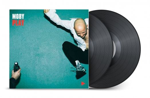 Обложка на албума Moby - Play (2 VINYL), на която е изобразен мъж с бяла риза и черни панталони, скачащ на тиландски фон, с две 180-грамови плоча винилови плочи, частично изпъкнали до обложката.