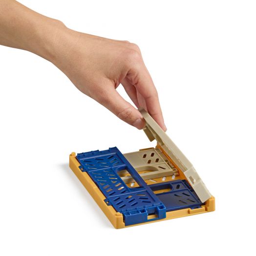 Ръката повдига бежовия капак на Сгъваема кутийка Apli Tricolor, Base Mustard - правоъгълна пластмасова STEM играчка със сини и жълти части, за да разкрие вътрешната ѝ структура.-4
