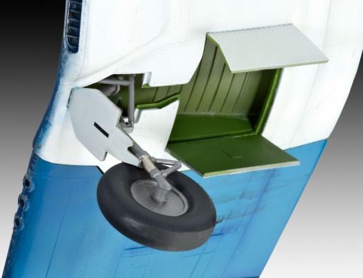 Близък план на частично разгънатото шаси с едно колело и детайлно отделение на сглобяем модел Revell - самолет F4U-1A Corsair, показващ зелени и бели панели на фона на синьо-белия фюзелаж.-7
