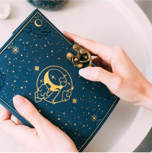Човек държи тефтер с корици от веган кожа Grupo Erik - Astral с тъмносиня корица, златен астрален дизайн и месингова закопчалка във форма на зъбни колела.-6
