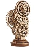 3D дървен пъзел Ugears - Steampunk Clock 2.0 (40 части) е механичен модел с преплетени зъбни колела и фини лазерно изрязани детайли, изправен върху кръгла основа.