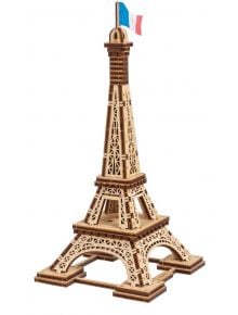 Показан е 3D дървен пъзел Ugears - Айфеловата кула Париж, 50 части, с детайлна решетка и френско знаме върху модела на Айфеловата кула, разположен върху равна повърхност на бял фон.