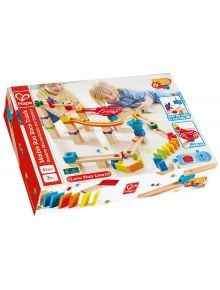 Две малки деца си играят с цветния Дървен комплект Hape - Състезателна писта с домино, 81 части, който включва дървени блокчета, писти, топчета и домино. На кутията е изобразена сглобената детска играчка и е подходяща за възраст 3+.