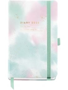 Джобен тефтер - органайзер Miquelrius Grafica Gradient 2026, ден на страница има пастелна акварелна корица в розово, бяло и тил със златен текст, ментовозелен ластик и перо, вдъхновени от стила Grafica Gradient.