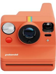 Polaroid Now+ Gen 3 Coral е оранжев фотоапарат с голям обектив, цветна лента, червен бутон и логото на Polaroid-идеален за моментални снимки навсякъде.