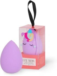 Лилавата Гъба за грим Legami - Еднорог е показана до кутията, на която е изобразен анимационен еднорог с грива на дъга, затворени очи, черна панделка отгоре и надпис "Legami Cutie Friends" отпред.