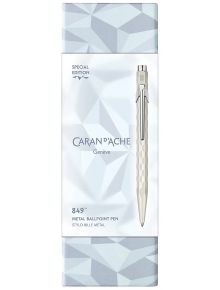 Химикалка Caran d'Ache 849 Alpine Frost, бяла, от ексклузивната колекция Alpine Frost, в сребриста кутия с геометричен мотив; пишещият инструмент е изобразен вертикално до логото и детайлите на продукта.